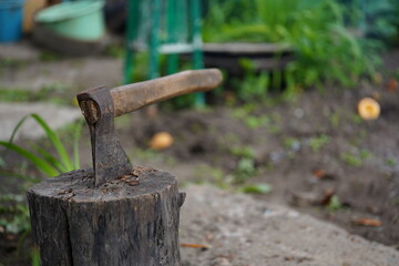 Fototapeta premium Close up of axe sticked in stump. Heavy instrument for chopping wood.