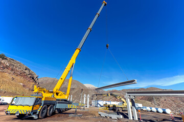 The big crane is lifting a concrete block for pipe bridge in the construction site.