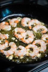 Process of frying giant red shrimps with garlic on olive oil on pan.