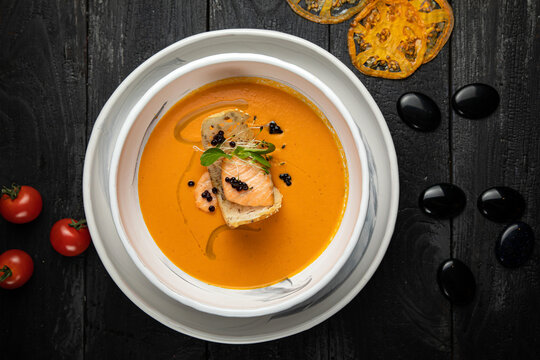 pumpkin soup with grilled salmon in a white plate. In the top restaurant
