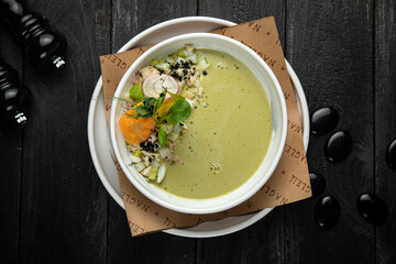 Top view of traditional Russian summer kefir or yogurt cold soup with vegetables called Okroshka. on a dark background