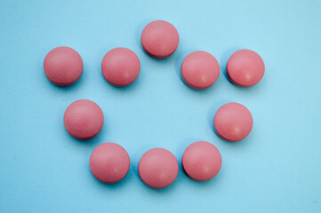 pink voluminous convex crown laid out in pills on a blue bright background. coronavirus infection. topical preparations for treating a person from a viral infection