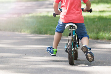 Little boy on a run bike in summer in the park. Balance bike concept.