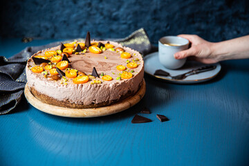 Homemade chocolate mousse cake with cumquats on blue background.