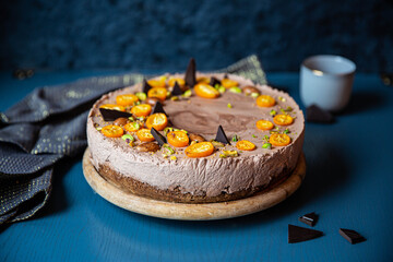 Homemade chocolate mousse cake with cumquats on blue background.