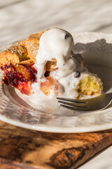 Piece of traditional apple pie with vanilla ice cream, and whole pie in ceramic baking form on white kitchen.