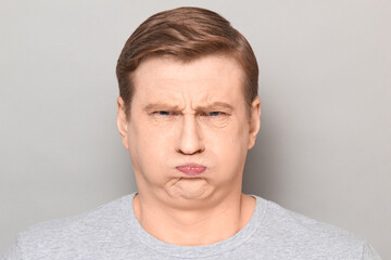 Portrait of funny goofy man puffing out his cheeks and pouting lips