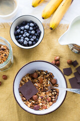 Making breakfast. Homemade granola with nuts, dark chocolate, bilberries and milk.