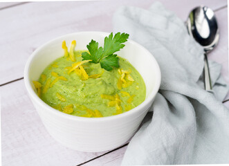 Vegetable green cream soup of cucumbers and avocado with lemon zest on a light background