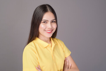 young confident beautiful woman wearing yellow shirt is on grey background studio