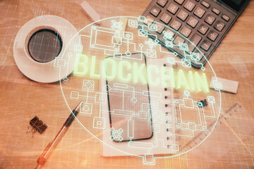 Double exposure of blockchain theme hologram over table with phone. Top view. Crypto technology...