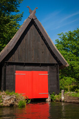 Small wooden boat house with red gate stands on the water in the town Lübbenau/Spreewald, Germany.