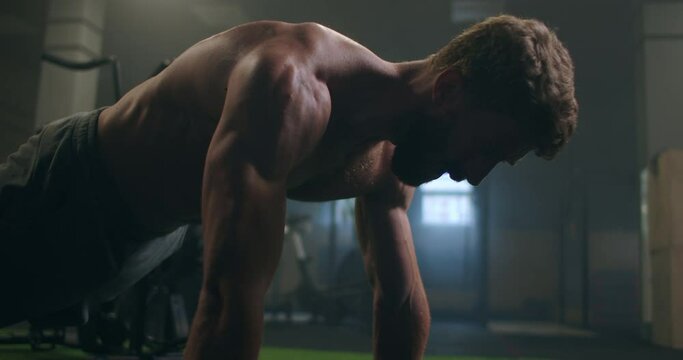 Man doing push ups in a gym. Exhaling and inhaling after push-ups and exercise. Perfect for fitness and workout. Young sports man performs pushups in the gym. The athlete is engaged in fitnes