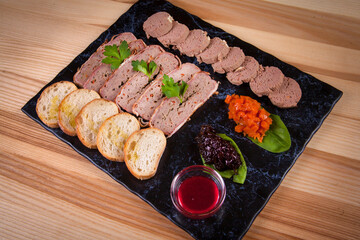 slicing pate with sauces with slices of bread on a stone platter