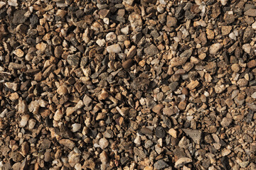 Small stones, pebbles on the ground. Texture. Brown Background