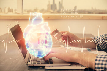 Double exposure of man hands holding a credit card and human heart drawing. Medical education and...