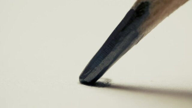 Graphite pencil draws a dot circle line on a white background paper, macro shot