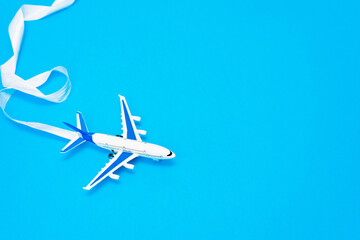 Flat lay design of travel concept with plane on blue background with copy space. The concept of flight, tourism and goal setting, leadership, prospects
