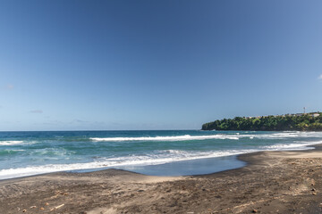 Black sand beach and breaking waves in Lorrain, Martinique, France