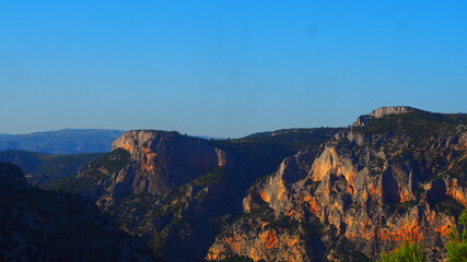 Colorful rugged mountains and pine trees with blue sky background