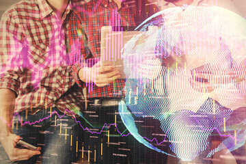 Double exposure of forex graph drawing and man and woman working together holding and using a mobile device. Trade concept.