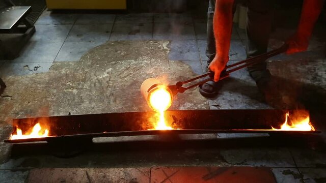 Molten silver being poured from a crucible into an ingot mold with the light coming from the molten silver. in the industrial workshop .  