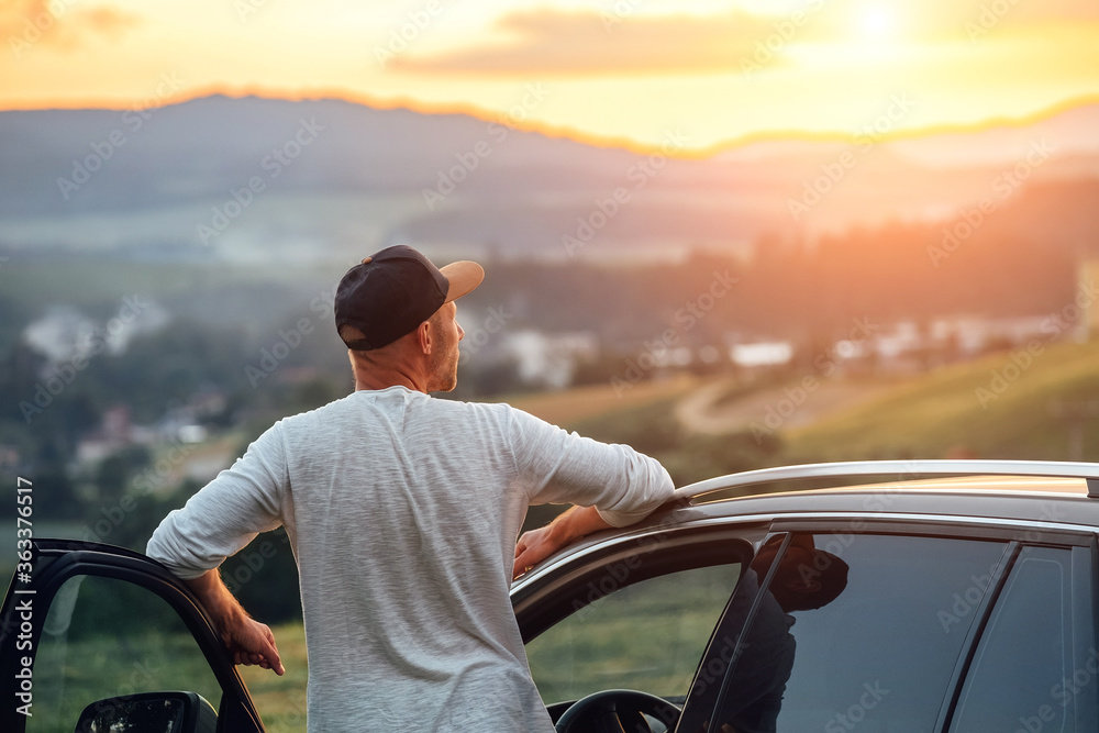 Wall mural young man having the long auto trip break. he stoped new car got out of the vehicle and enjoying the