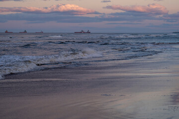 Ships in a beautiful reflective ocean with beautiful sky backdrop and glistening beach