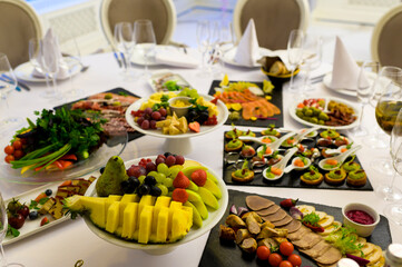 vegetables and fruits and cold snacks on a served table with glass glasses at a restaurant reception