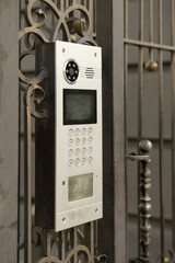 video intercom with buttons mounted on an iron fence in a large multi-storey building