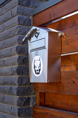 chromed mail box for mail outside the building on a wooden fence