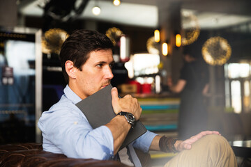 Handsome stylish man sitting in cafe and thinking about the book he is reading