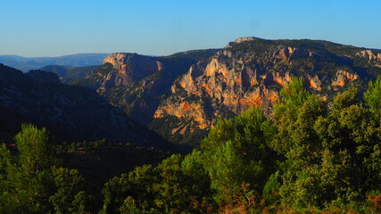 Obraz premium Colorful rugged mountains and pine trees with blue sky background