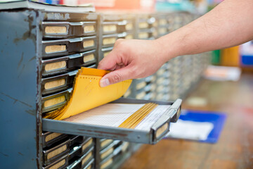 Hand find old stock card in a metal file cabinet. Manual control product system in old warehouse. The concept of old database system.