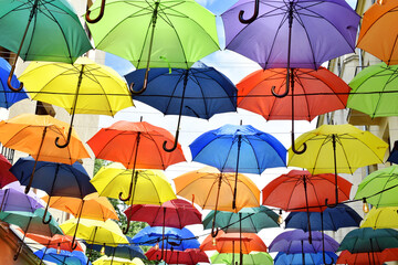 Fototapeta na wymiar colorful umbrellas hanging between buildings over blue sky