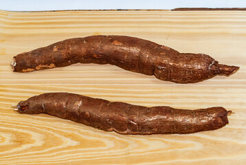 Raw yucca on the wooden table, Manihot esculenta. (Cassava raw tuber). Cassava, also called mandioca, yuca, balinghoy, mogo, mandioca, kamoteng kahoy, tapioca and tapioca root. Focus selective.