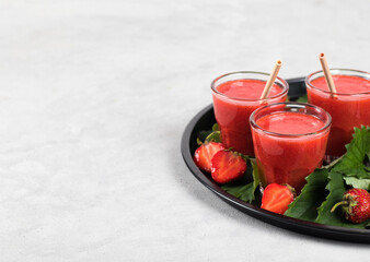 Strawberry smoothie in a jar with straws on a light background