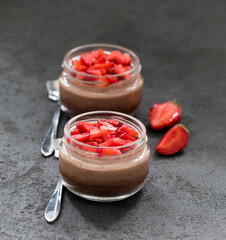Dessert cream cheese chocolate strawberry cheesecake in a jar on a dark gray background