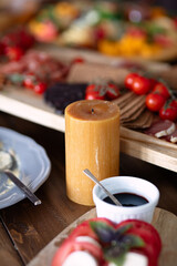 brown wax candle stands on  table with food, colorful dishes on  background, selective focus, festive dinner,