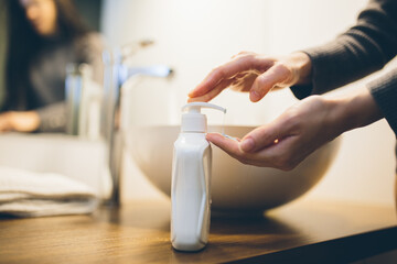 Young woman wash hands with soap in bathroom. Trendy coronavirus covid-19 concept