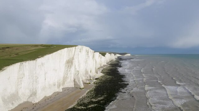 Aerial drone pullback shot of Seven Sisters and Birling Gap with dramatic cloudy sky and the sea below