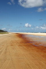 Beautiful image of Fraser Island along 75 miles beach showing blue sky, sand, water and waves