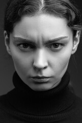 Obraz premium Attractive brunette girl in a dark sweater poses for the camera. black and white image