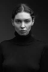 Attractive brunette girl in a dark sweater poses for the camera. black and white image