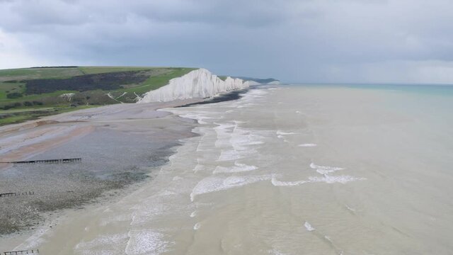 Aerial drone wide establishing shot of Seven Sisters and Birling Gap with dramatic cloudy sky and the sea below