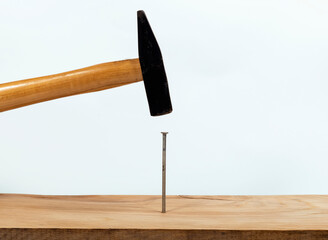Hammer with a steel nail in a wooden board