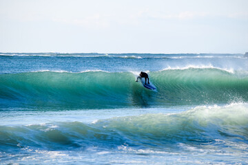 Surfer on Blue Ocean Wave riding on surfing board in Asia.  Japan is famous for its great waves near to Tokyo City