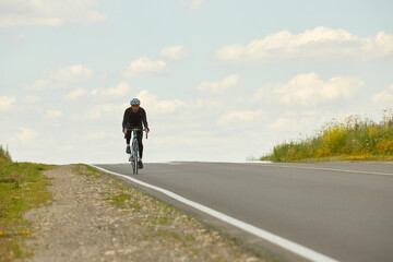 Obraz premium Road bike male cyclist on a Bicycle. Bicycle sport fitness athlete riding a bike on the road. Active healthy sports lifestyle of an athlete on a Bicycle outside of triathlon training on an summer day
