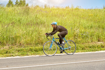 Obraz premium Professional cyclist climbs the mountain on an open paved road, beautiful nature on the horizon on a Sunny day.