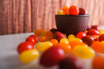 Various colorful cherry tomatoes on white and wooden background. Creative design, beautiful lighting.
